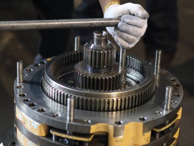 Şanzıman üzerinde çalışan bir insanın elleri, uzun saplı ve endüstriyel ayarlarla cıvatayı sıkma sürecini vurguluyor..