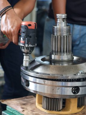 Çalışan atölyede hassas dişli gezegensel teçhizat montajı üzerinde güç etkisi kullanıyor.