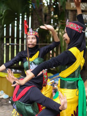 Balikpapan-Endonezya 21 Eylül 2025 geleneksel kostüm ve başlık giyen genç Dayak dansçıları, bir kadın bıçak ısırma eylemi yapıyor, kültürel bir performansın bir anını yakalıyor.