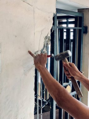 Close-up of worker breaking concrete wall with hammer and chisel, showing raw strength and focus. Perfect for construction, renovation, engineering, labor, and demolition concepts.