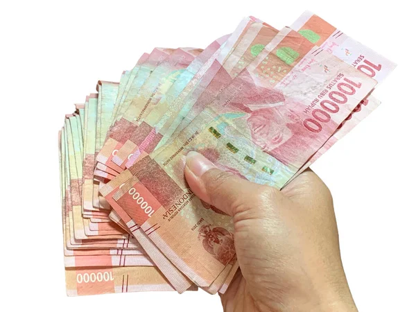 Hand holds the spreading Indonesian 100,000 rupiah bills isolated on white background. Sharp detail, natural light, perfect for finance, economy, banking, salary, savings, and wealth themes.
