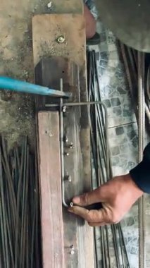 4K close-up of worker bending steel rebar rods with plier hand tool. Sharp focus highlights strength, precision, and labor. Great for construction, engineering, architecture, and industry concepts.