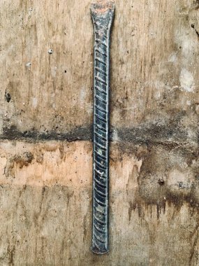 Top view of rusted chisel bar on wooden surface. Sharp focus shows rustic texture and grit. Perfect for construction, industry, repair, and grunge background themes.