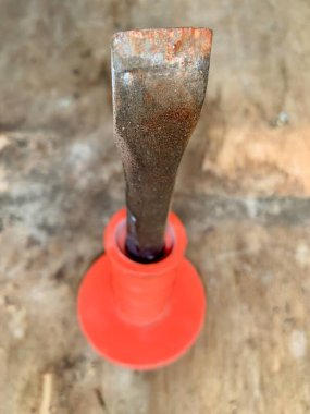 Yıpranmış kenarı ve turuncu sapı olan paslı keski bıçağının yakın çekimi. Keskin bir detay ve bulanık arka plan, dayanıklılık ve metaneti vurguluyor. Temalar için harika: endüstri, araçlar, işçilik, vintage zanaat.