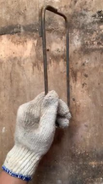 4K footage of gloved hand holding rusted rebar frame on rustic wood. Sharp textures highlight strength, grit, and hard labor. Perfect for construction, industrial themes, etc. Real time motion.
