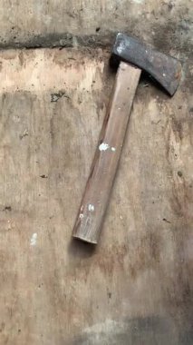 Ahşap saplı yıpranmış bir balta ve kaba ahşap yüzeye yerleştirilmiş paslı çelik kafa. 4K 'da doğal ışıkla çekilmiş, kırsal dokuyu gösteriyor. Çalışmaya, hayatta kalmaya, çiftçiliğe ve mahsullere elverişli.