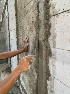 Hand of construction worker plastering cement on wall with trowel, showing detail and texture. Great for themes of building, renovation, architecture, labor, and craftsmanship.