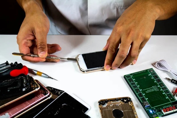 process to change mobile phone batteries Step 3 : The repairman is using the tool to see the battery inside the mobile phone.