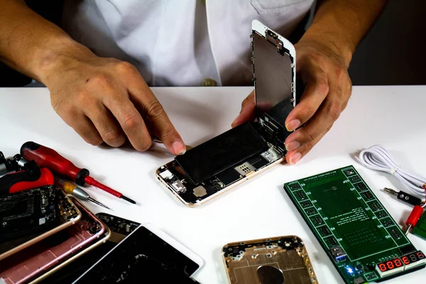 process to change mobile phone batteries Step 4 : The repairman is removing the battery from the mobile phone.