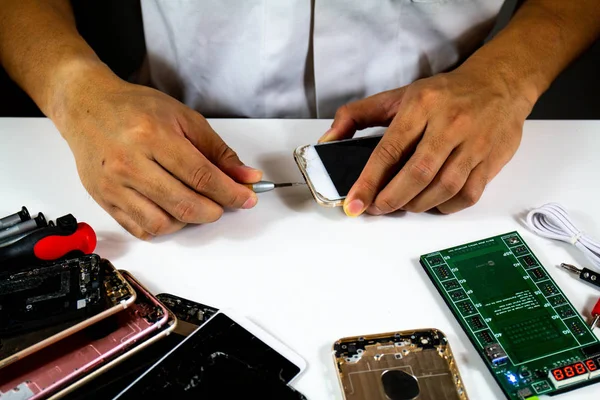 process to change mobile phone batteries Step 2 : The repairman is tightening the nut to see the battery inside the mobile phone.