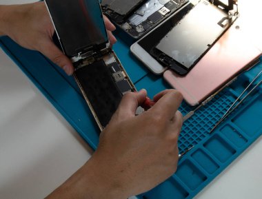Cep telefonu tamircisinin masasında cep telefonunu söküyor.