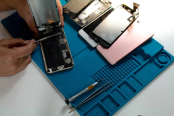 The mobile repairman is removing the mobile phone screen in order to replace the damaged parts from being dropped.