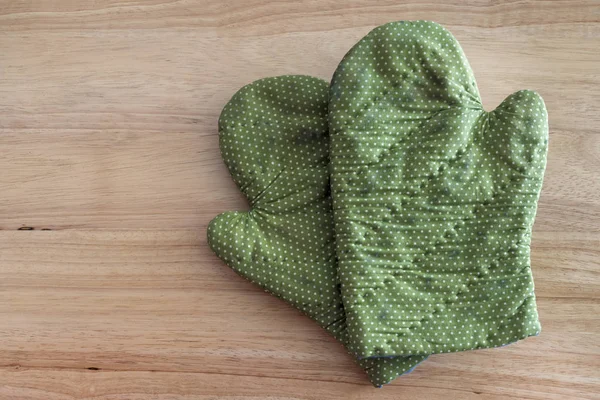 Green glove on a wooden table. Kitchen cooking utensils top View.