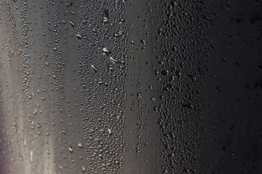 Sabahın erken saatlerinde güneş fotoğraflandı siyah poliüretan sayfasındaki çiy damlacıkları.