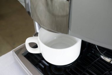 Beyaz fincan kahve makinesi altında