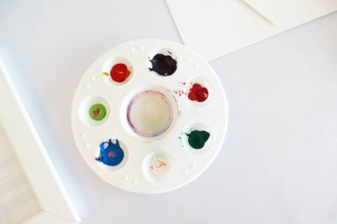 Çok renkli suluboya içinde bir yuvarlak beyaz plastik tepsi.