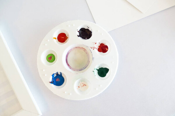 Multicolored watercolor in a round white plastic tray.