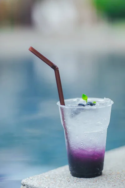 Fresh cold drink with blueberry and sweet soda, cold at the pool. Healthy beverage in a rustic style. Trendy lifestyle drink.