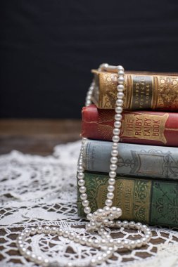 Bir dantel doily üzerinde çay fincanı ve inci ile Kitaplar