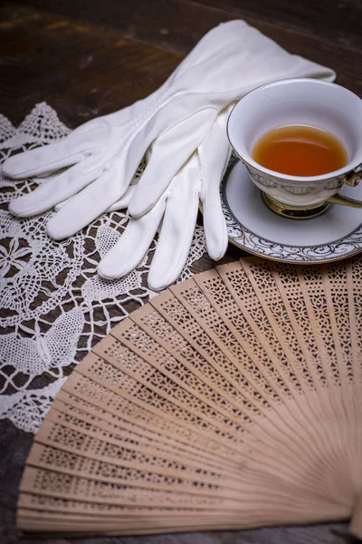 Vintage fan with gloves, pearls and other items on a dressing table