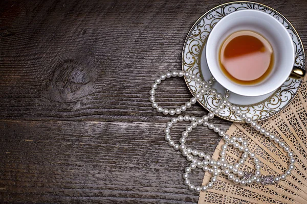 Bir dantel doily üzerinde çay fincanı ve inci ile Kitaplar