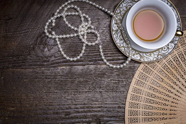 Bir dantel doily üzerinde çay fincanı ve inci ile Kitaplar