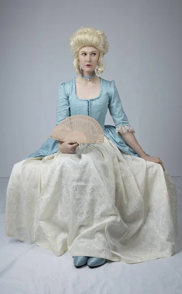 18th-century woman in a blonde wig and a blue dress