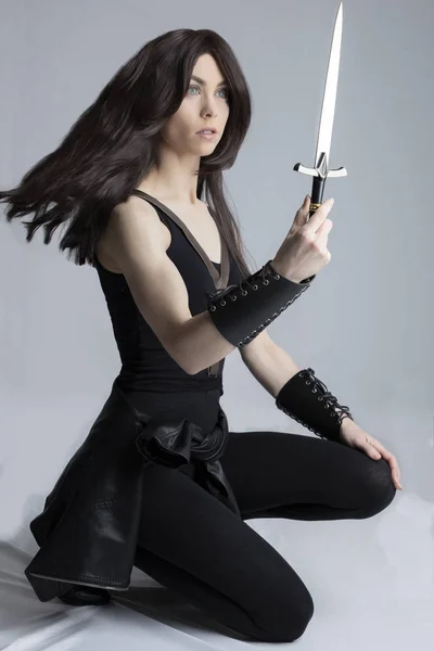 Elf-like woman in fantasy style pose holding a dagger