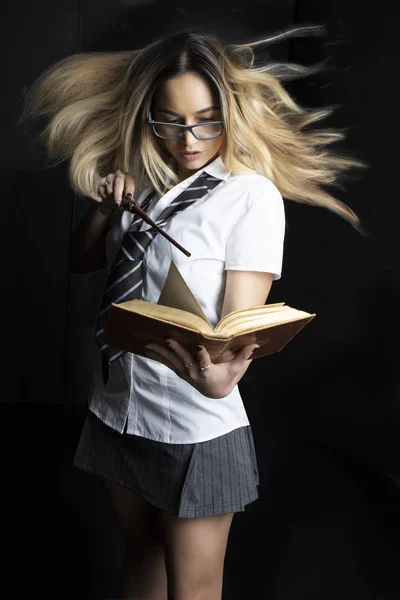 Schoolgirl witch with a book of magic spells - digital composite