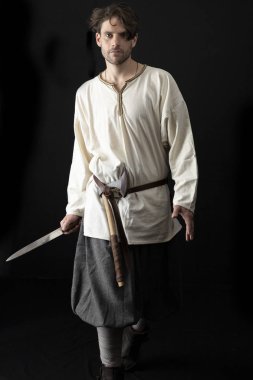 Ortaçağ ya da Viking kostümü giymiş koyu saçlı bir adam.