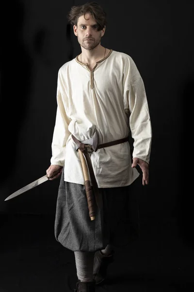 Ortaçağ ya da Viking kostümü giymiş koyu saçlı bir adam.