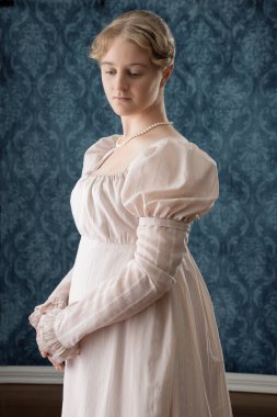 Genç bir naip kadın pembe bir elbise ve inci bir kolye giyiyor. 