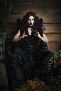 Cadılar Bayramı temalı siyah gotik bir tahtta oturan bir kadın.