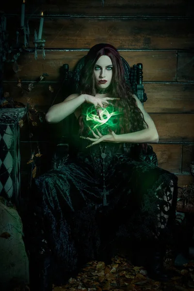 A woman seated on a black gothic throne in a Halloween themed image
