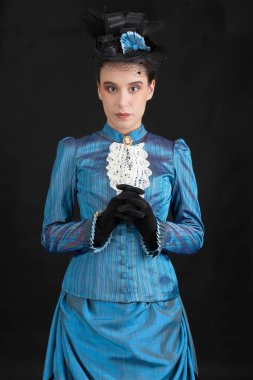 1880 'lerdeki Victoria tarzı genç bir kadın siyah bir stüdyo arkaplanına karşı çıkıyor.