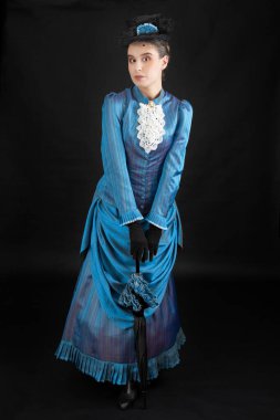 1880 'lerdeki Victoria tarzı genç bir kadın siyah bir stüdyo arkaplanına karşı çıkıyor.