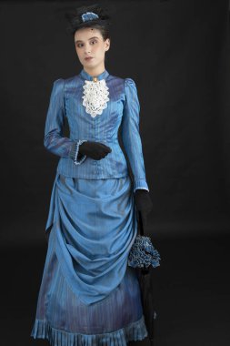 1880 'lerdeki Victoria tarzı genç bir kadın siyah bir stüdyo arkaplanına karşı çıkıyor.