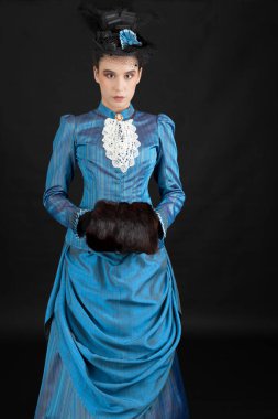 1880 'lerdeki Victoria tarzı genç bir kadın siyah bir stüdyo arkaplanına karşı çıkıyor.