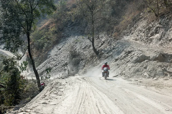 Dağlarda tozlu toprak yol üzerinde sürüş bir motosiklet.