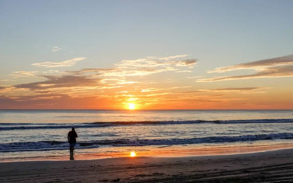 Bazı insanlar gün batımı sırasında sahilde su.