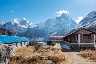 Bir taş ev ve Himalaya Dağları yorgun yürüyüşçülerin için bir durak olarak.
