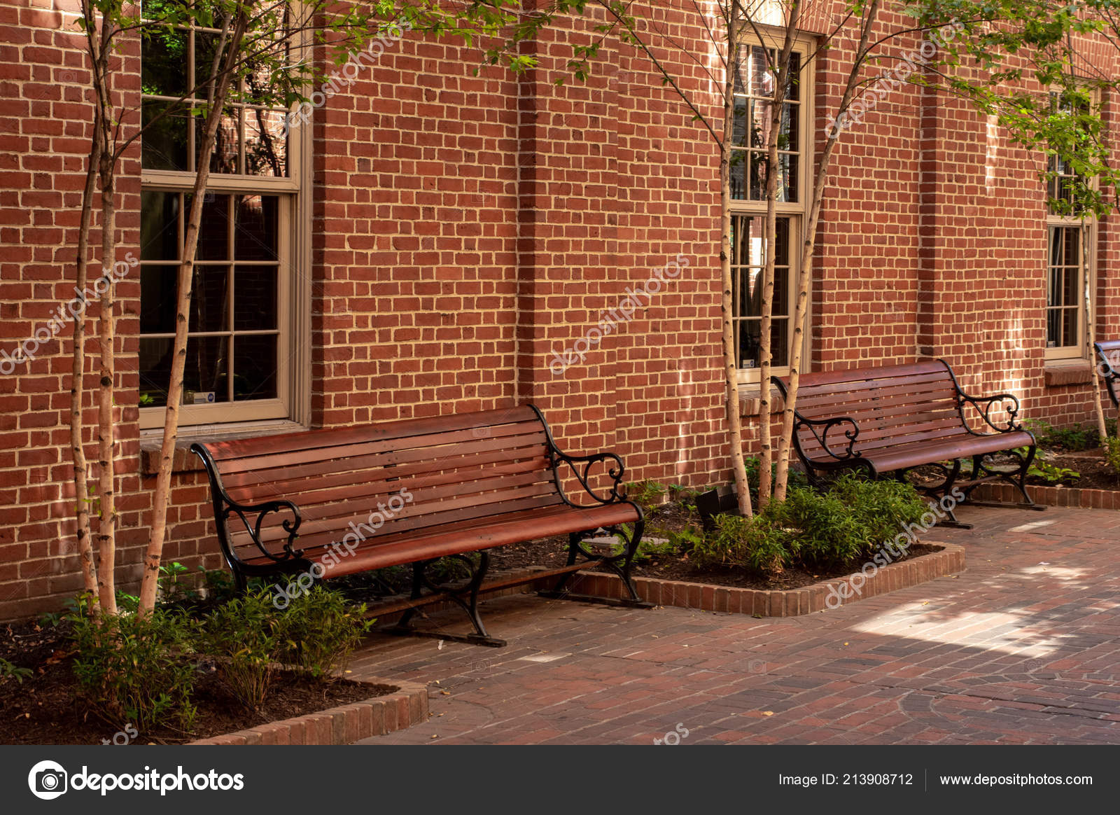 Some Park Benches Sitting Alongside Brick Building Stock Photo