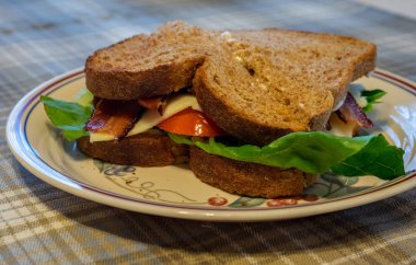 Bacon marul domates peynirli sandviç bir plaka üzerinde.