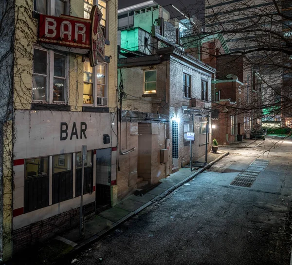 A dark alleyway in the downtown district of a city.