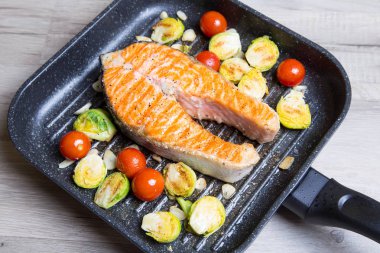 Brüksel lahanası, kiraz ve sarımsak pan ızgara somon biftek. Yakın çekim, seçici odak.