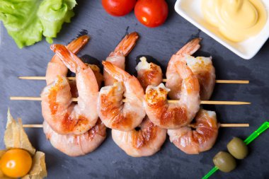 Prosciutto bir kara tahta üzerinde soslu karides ızgara. Yakın çekim, seçici odak.