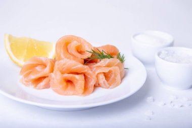 Limon ve dereotu ile beyaz bir tabakta tuzlu somon. Beyaz arka plan, seçici odaklama, yakın çekim.