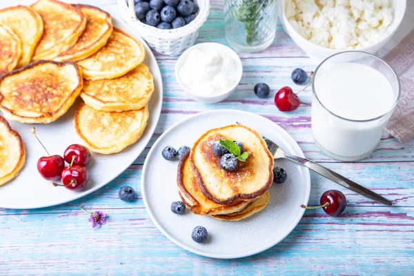 Cottage cheese pancakes (syrniki). Homemade cheesecakes from cottage cheese with sour cream, berries and milk. Traditional Russian dish. Close-up.