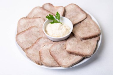 Beyaz bir tabakta yabanturpu ile sığır haşlanmış dil. Beyaz arka plan, izole edilmiş. Close.