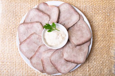 Beyaz bir tabakta yabanturpu ile sığır haşlanmış dil. Close.